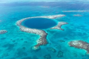 An aerial photo of the Great Blue Hole off the coast of Belize. A coral reef is seen in the blue waters.