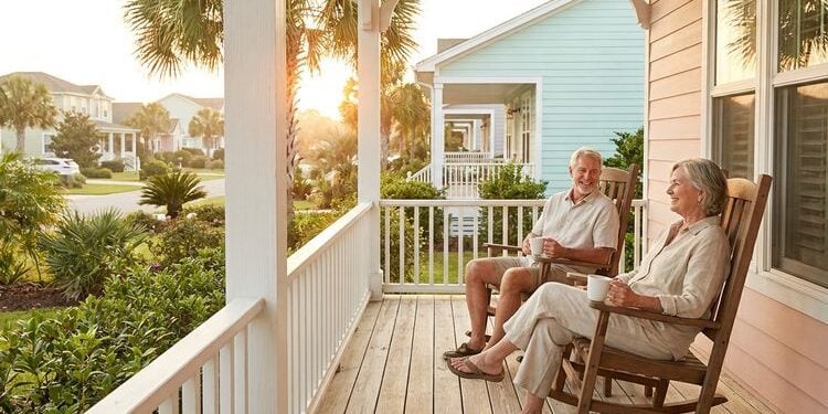 Retired couple relaxing on the porch of a coastal home at sunset