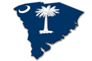 An image of the flag of South Carolina overlaid on a map of South Carolina. The flag features a crescent moon and palm tree on a blue background